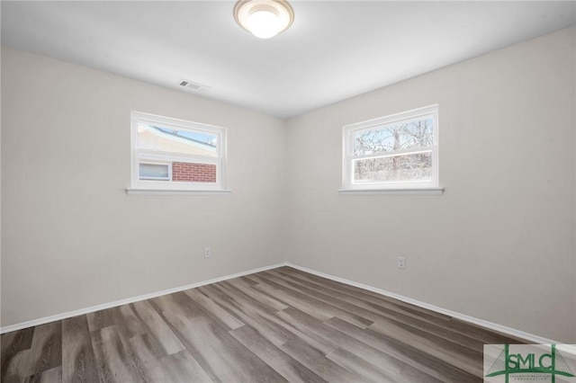 unfurnished room featuring visible vents, baseboards, and wood finished floors