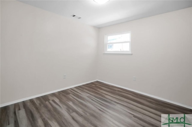 spare room with visible vents, baseboards, and dark wood-style flooring