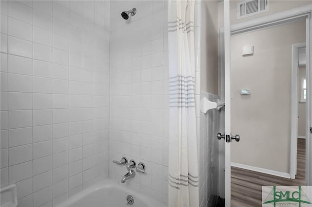 full bathroom featuring visible vents, wood finished floors, baseboards, and shower / bath combo