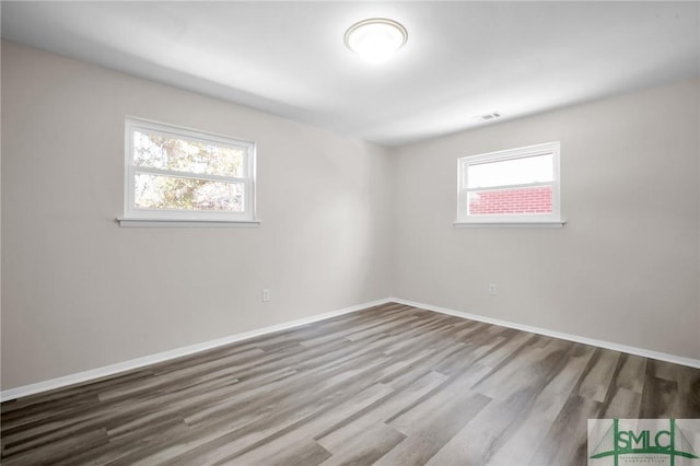 empty room featuring visible vents, baseboards, and wood finished floors