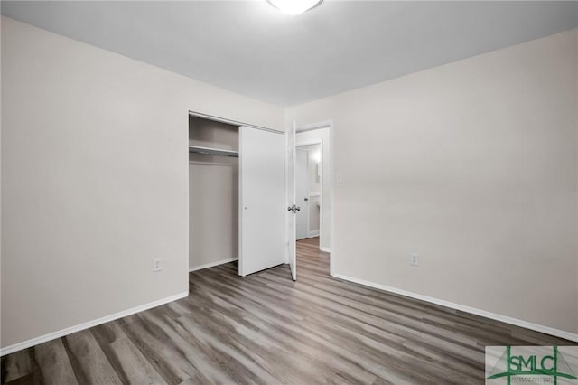 unfurnished bedroom featuring a closet, baseboards, and wood finished floors