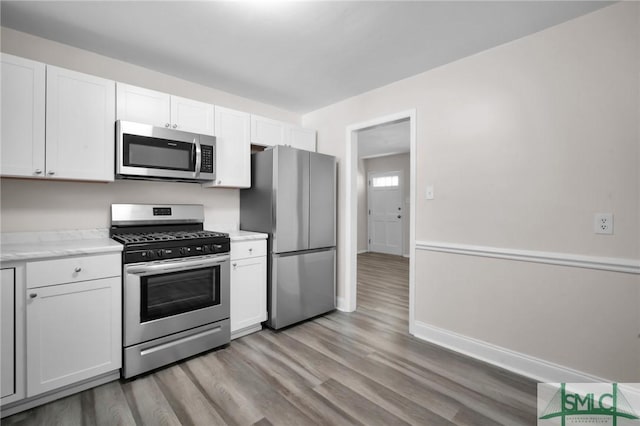 kitchen with light wood-style flooring, appliances with stainless steel finishes, white cabinets, and light countertops