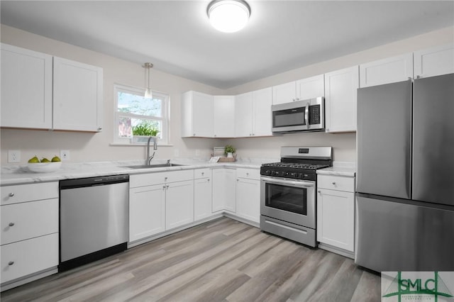 kitchen with white cabinets, light wood-style flooring, appliances with stainless steel finishes, and a sink