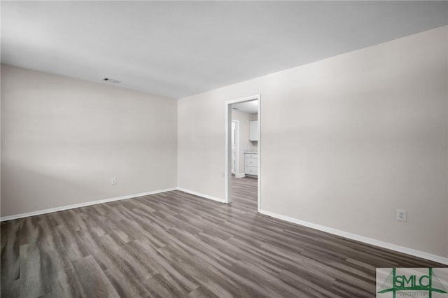 unfurnished room with dark wood finished floors, baseboards, and visible vents