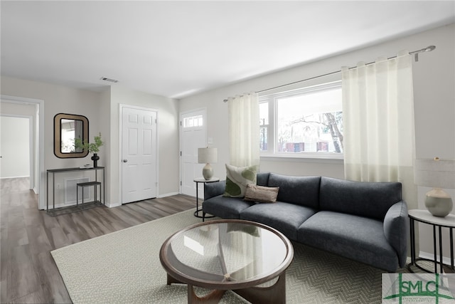 living area with visible vents, baseboards, and wood finished floors