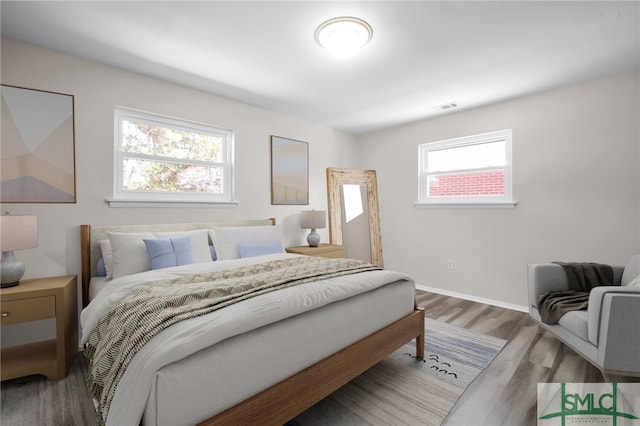 bedroom featuring wood finished floors, visible vents, and baseboards