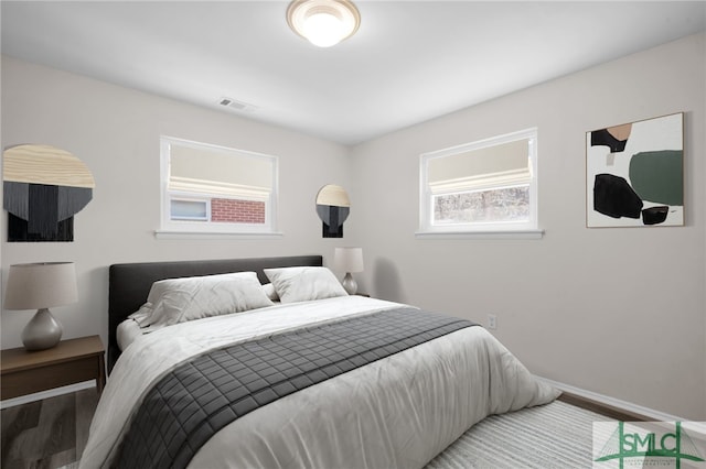 bedroom featuring wood finished floors, baseboards, and visible vents