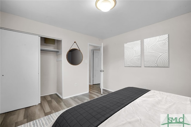 bedroom with a closet, baseboards, and wood finished floors