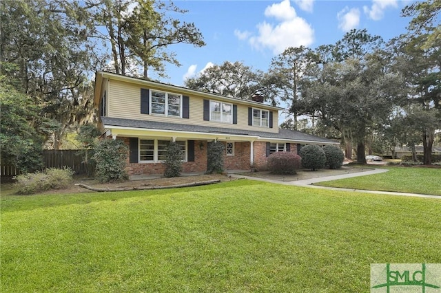 view of front facade featuring brick siding, a chimney, a front yard, and fence