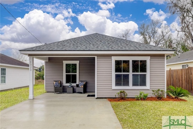 back of property with fence, a lawn, and roof with shingles