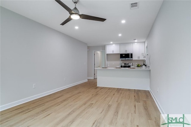 kitchen featuring visible vents, light wood-style flooring, appliances with stainless steel finishes, a peninsula, and white cabinetry