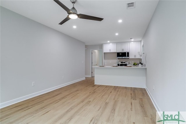1323 E 69th St, Savannah, GA 31404 - kitchen with stainless steel appliances, a peninsula, white cabinetry, light wood-type flooring, and light countertops