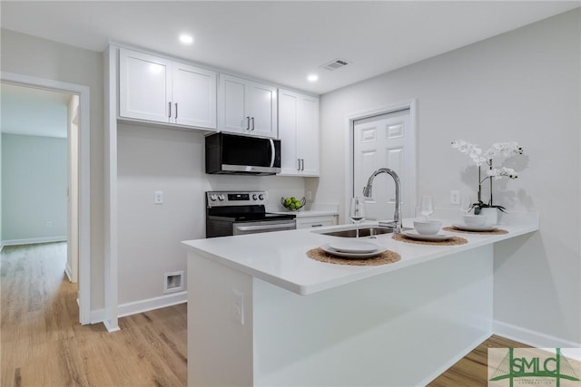 1323 E 69th St, Savannah, GA 31404 - kitchen with appliances with stainless steel finishes, white cabinets, a sink, light wood finished floors, and recessed lighting