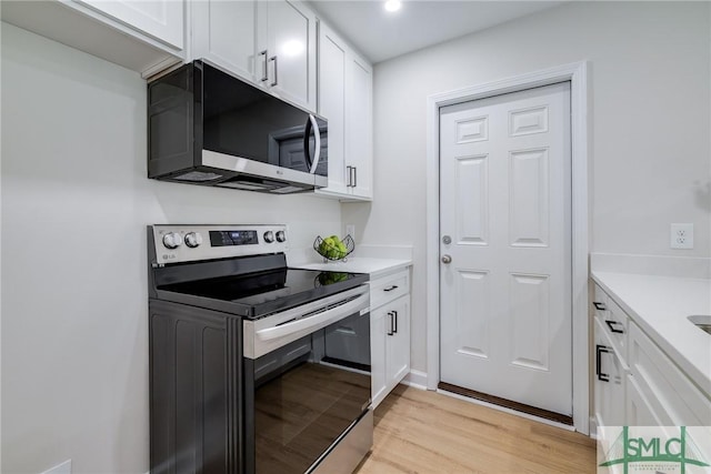 kitchen featuring white cabinets, stainless steel electric range oven, light wood-type flooring, and light countertops