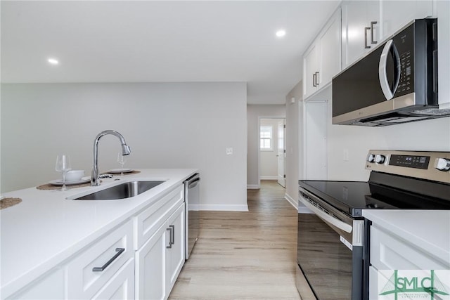 kitchen featuring a sink, light wood-style flooring, appliances with stainless steel finishes, and white cabinets