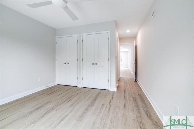 unfurnished bedroom with light wood-style flooring, baseboards, two closets, and ceiling fan