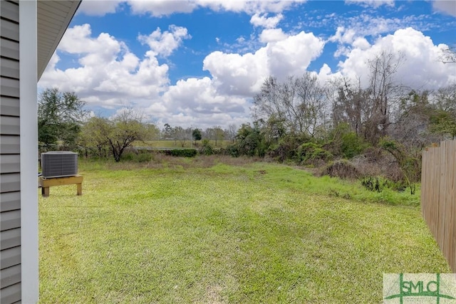 view of yard featuring central AC and fence