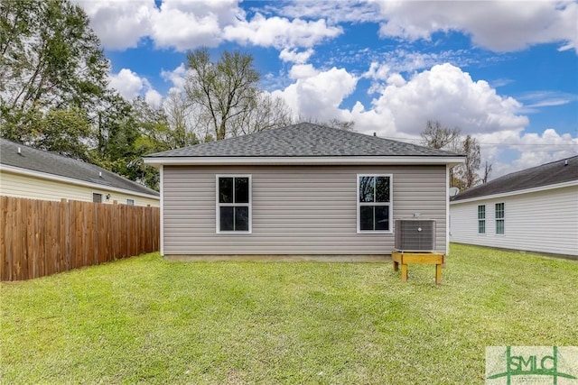 back of house featuring central air condition unit, a yard, fence, and a shingled roof