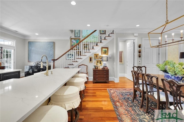 dining room featuring recessed lighting, light wood-type flooring, crown molding, and stairs