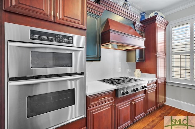 kitchen with crown molding, dark wood-type flooring, premium range hood, light countertops, and stainless steel appliances