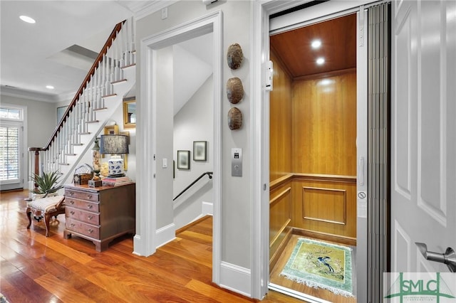 interior details with elevator, recessed lighting, crown molding, and wood finished floors