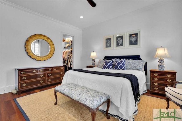 bedroom featuring ornamental molding, a ceiling fan, wood finished floors, a closet, and a spacious closet