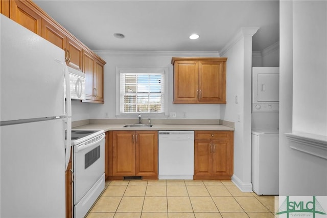 kitchen featuring white appliances, stacked washer and dryer, light countertops, and brown cabinets