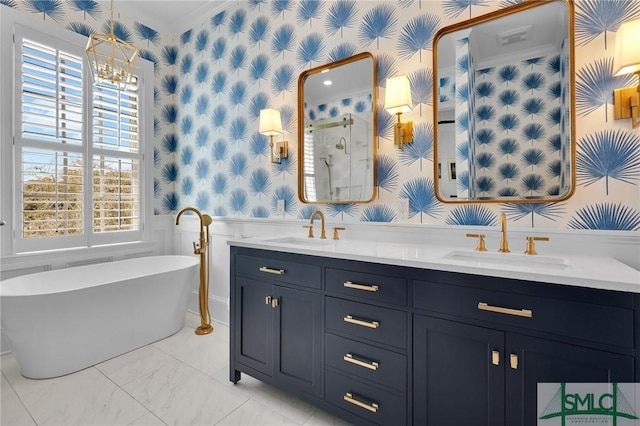 bathroom featuring wallpapered walls, a freestanding tub, a sink, and wainscoting