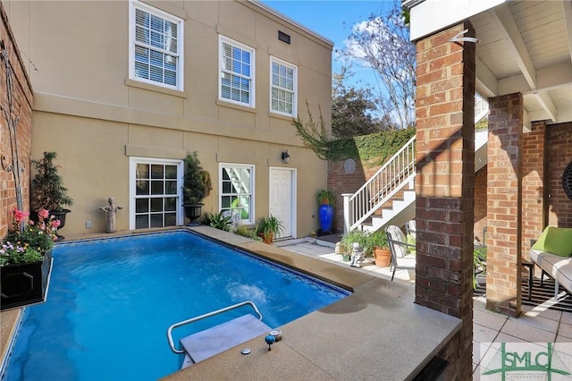 outdoor pool with stairs and a patio area