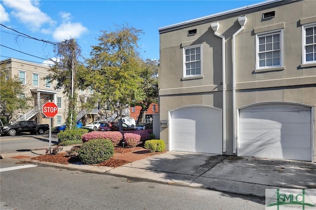 view of front of property featuring concrete driveway, an attached garage, and stucco siding