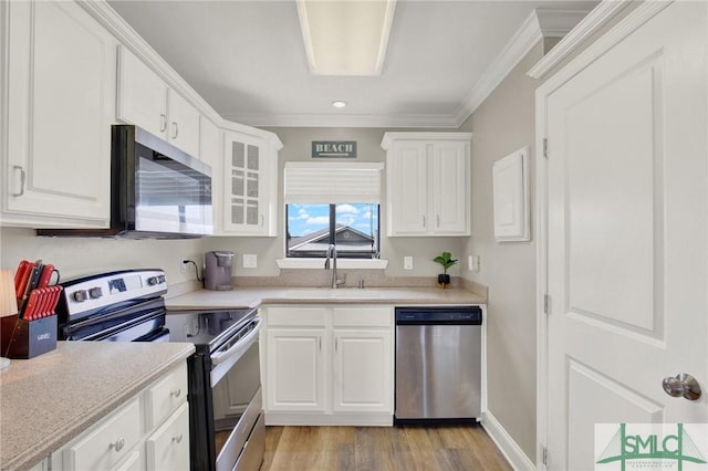 kitchen featuring white cabinetry, appliances with stainless steel finishes, ornamental molding, and light countertops