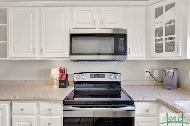 kitchen with white cabinetry, light countertops, glass insert cabinets, and appliances with stainless steel finishes