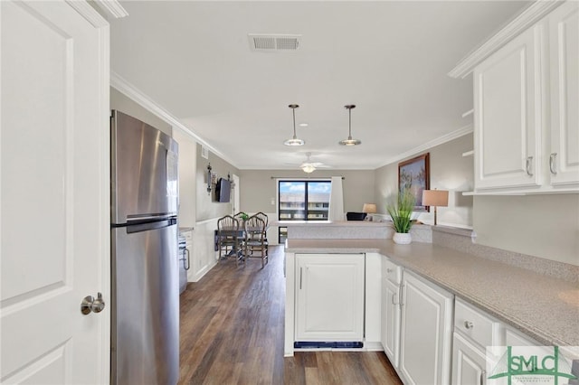 kitchen featuring visible vents, crown molding, a peninsula, freestanding refrigerator, and white cabinets