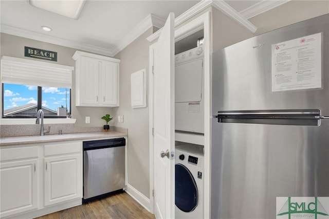 kitchen with light countertops, ornamental molding, white cabinets, stainless steel appliances, and a sink