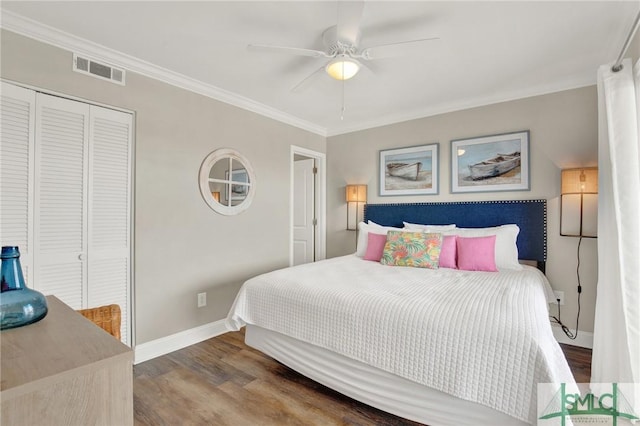 bedroom with visible vents, crown molding, baseboards, wood finished floors, and a closet