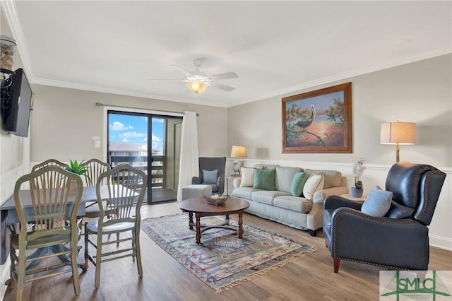 living area with wood finished floors, a ceiling fan, and ornamental molding