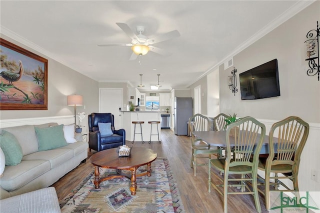 living area with light wood finished floors, visible vents, crown molding, and ceiling fan