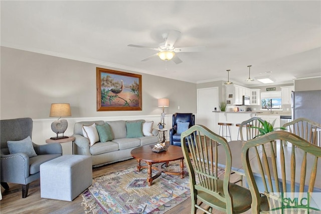 living room featuring light wood finished floors, crown molding, and ceiling fan