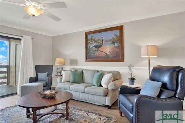 living area with a ceiling fan, wood finished floors, and ornamental molding