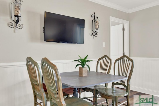 dining area with wainscoting, crown molding, and wood finished floors