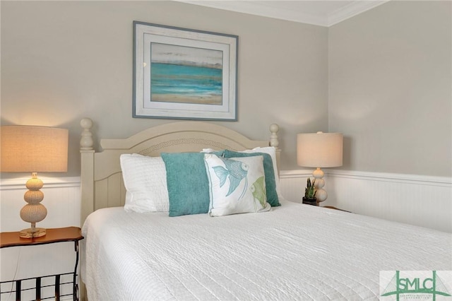 bedroom with a wainscoted wall and crown molding