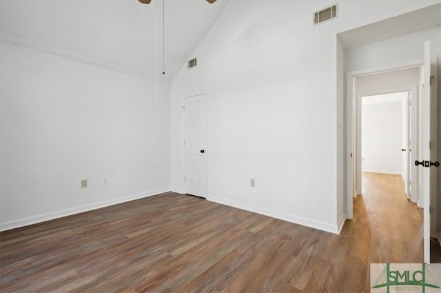 empty room featuring wood finished floors, baseboards, a ceiling fan, visible vents, and high vaulted ceiling