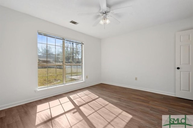 spare room featuring ceiling fan, visible vents, baseboards, and wood finished floors