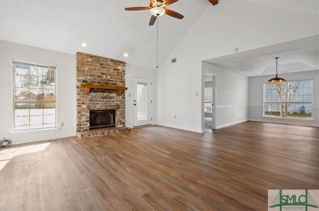 unfurnished living room featuring wood finished floors, a ceiling fan, visible vents, baseboards, and a fireplace