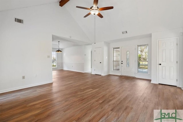 unfurnished living room with wood finished floors, a ceiling fan, visible vents, beam ceiling, and plenty of natural light