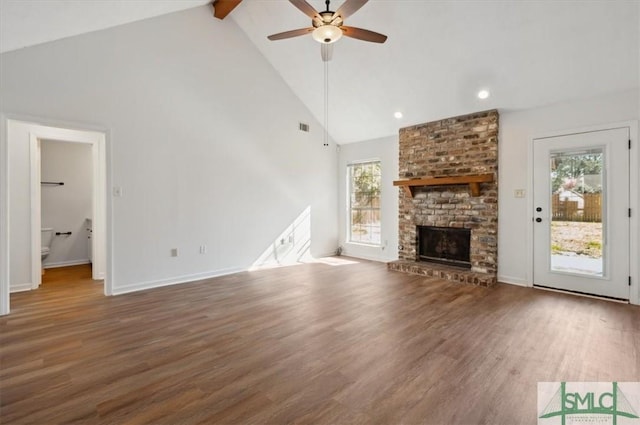 unfurnished living room with beam ceiling, high vaulted ceiling, wood finished floors, a fireplace, and ceiling fan