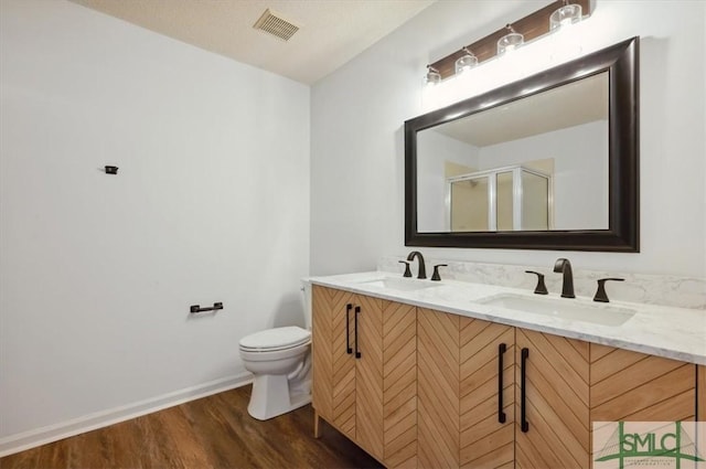 bathroom with double vanity, wood finished floors, visible vents, and a sink