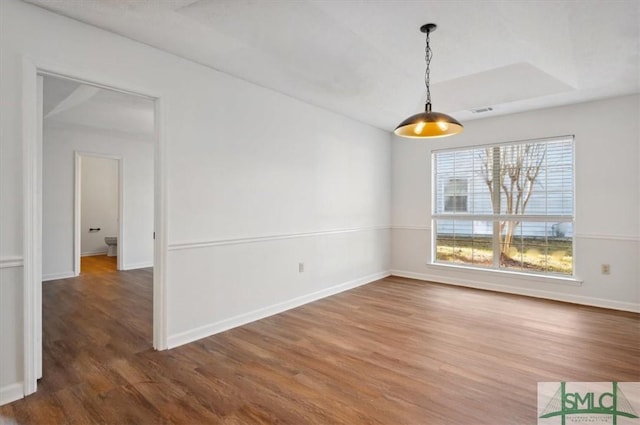 unfurnished dining area with visible vents, baseboards, and wood finished floors