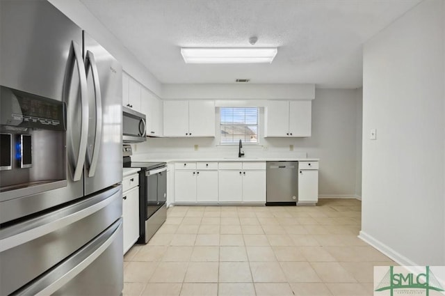 kitchen featuring light countertops, white cabinets, appliances with stainless steel finishes, and a sink