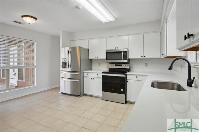 kitchen featuring visible vents, light countertops, appliances with stainless steel finishes, white cabinetry, and a sink